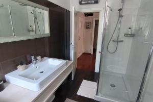ein Badezimmer mit einem weißen Waschbecken und einer Dusche in der Unterkunft Apartman Sonja in Lovran