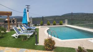 a swimming pool with two chairs and an umbrella at Seaview Villa in Néa Epídhavros