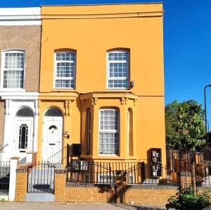 ein gelbes Haus mit einem Zaun davor in der Unterkunft Lovely 3bedroom Apartment London in London