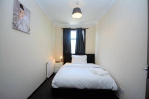 ein kleines Schlafzimmer mit einem weißen Bett und einem Fenster in der Unterkunft Lovely 3bedroom Apartment London in London