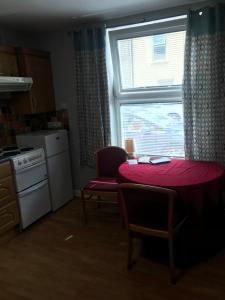 een keuken met een rode tafel en een raam bij City centre apartments free Wi-Fi free parking in Derry Londonderry