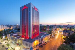 ein hohes Gebäude mit roten Lichtern in einer Stadt in der Unterkunft Sheraton Bucharest Hotel in Bukarest