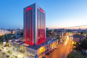 een hoog gebouw met rode lichten aan in een stad bij Sheraton Bucharest Hotel in Boekarest