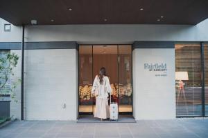 a woman is standing outside of a building holding a suitcase at Fairfield by Marriott Gifu Gujo in Gujo