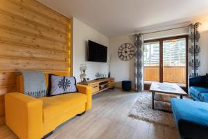 - un salon avec un canapé jaune et un mur en bois dans l'établissement Apartament Sobiczkowa Zakopane, à Kościelisko