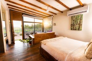 a bedroom with a large bed and a large window at Brisa Del Valle Hotel Boutique in Valle de Guadalupe