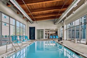 an indoor pool with blue chairs and windows at Aloft Arundel Mills BWI Airport in Hanover