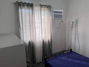 a room with a bed and a window with curtains at Sidra Ville Apartment in Balanga