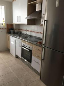 kuchnia z białymi szafkami i lodówką ze stali nierdzewnej w obiekcie Superbe appartement avec piscine à 800m de la mer w mieście Bahia de Casares