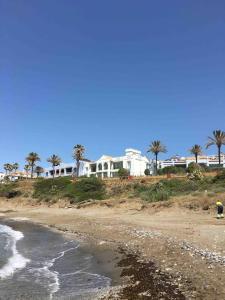 plaża z białym domem i palmami w obiekcie Superbe appartement avec piscine à 800m de la mer w mieście Bahia de Casares