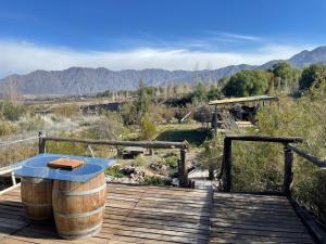 a wooden deck with a table and a barrel at Andes Sol y río cabañas vacacionales en la montaña mendoza in Las Compuertas