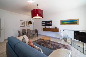 BarBar apartment - STYLE & RELAX في مارون: غرفة معيشة مع أريكة زرقاء وغرفة طعام