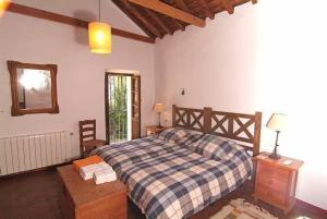 een slaapkamer met een bed met een geruite deken bij Molino del Caracol in Benaoján