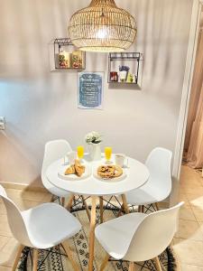 a white dining room with a white table and chairs at Davanti al Mare in Epanomi