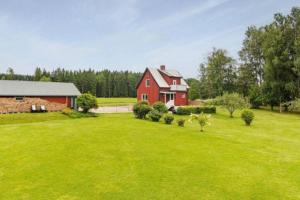 a red barn in a field with a green yard at Schwedische Landidylle für die ganze Familie in Dingelvik