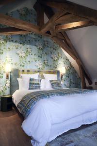 a bedroom with a white bed with floral wallpaper at Les Deux Marguerite in Alençon