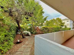 a garden with a retaining wall and a tree at Beach house with private garden and parking in Grado-Pineta