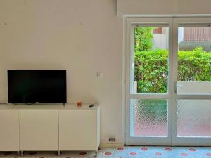 a living room with a tv and a sliding glass door at Beach house with private garden and parking in Grado-Pineta