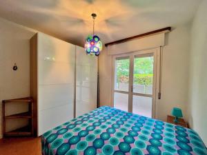 sypialnia z niebieskim łóżkiem i oknem w obiekcie Beach house with private garden and parking w mieście Grado-Pineta
