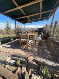 un patio con mesa y sillas bajo un techo en Andes Sol y río cabañas vacacionales en la montaña mendoza en Las Compuertas