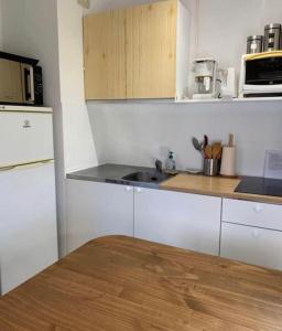 a kitchen with white cabinets and a wooden counter top at Studio 27 m2 avec terrasse 20m2 in Six-Fours-les-Plages