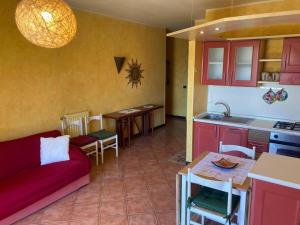 uma sala de estar com um sofá vermelho e uma cozinha em Casa di Ro - coloratissima a 300 metri dal mare em San Bartolomeo al Mare