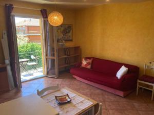 uma sala de estar com um sofá vermelho e uma mesa em Casa di Ro - coloratissima a 300 metri dal mare em San Bartolomeo al Mare