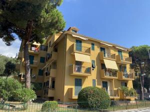 een geel appartementencomplex met ramen en een boom bij Casa di Ro - coloratissima a 300 metri dal mare in San Bartolomeo al Mare