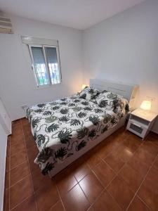 a bedroom with a bed with a black and white comforter at Casa de Fernando in Puerto Real