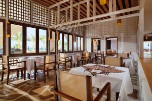 a restaurant with white tables and chairs and windows at Retac Qunay Dahab Resort & SPA in Dahab