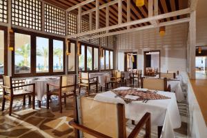 um restaurante com mesas e cadeiras brancas e janelas em Retac Qunay Dahab Resort & SPA em Dahab