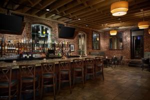 un bar con taburetes de madera y una pared de ladrillo en Craddock Terry Hotel, Lynchburg, a Tribute Portfolio Hotel, en Lynchburg