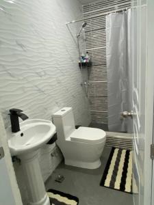 a white bathroom with a toilet and a sink at Tiny Apartment By Merengue House in Santo Domingo