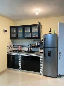 d'une cuisine équipée d'un réfrigérateur en acier inoxydable et de placards noirs. dans l'établissement Tiny Apartment By Merengue House, à Saint-Domingue