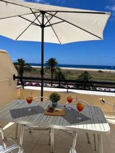 a table with an umbrella on a balcony with the beach at Apartamento perla marina in Morro del Jable