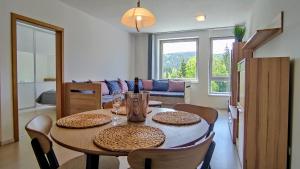 een eettafel met stoelen en wijnflessen erop bij Moderní a slunný apartmán 2KK v Anenském Údolí se sklepem a parkováním - by Relax Harrachov in Harrachov