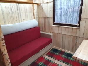 a red couch in a cabin with a window at Planinska Bajka pogodna za dnevne boravka i one koji se vole in Olovo