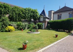 une maison avec une cour avec des pots de fleurs dans l'herbe dans l'établissement Le Clos Saint-Germain, à Rugles