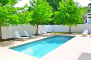 マートルビーチにあるThe Palm Luxury Beach House with Pool Top Locationの庭園内の木々と椅子付きのスイミングプール