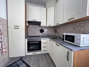 een keuken met witte kasten en een magnetron bij Stefano's Guests House: 2 bedrooms & parking in Viareggio in Viareggio