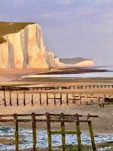 a wooden fence on the beach with a large cliff at Sandford House Apartment in Seaford