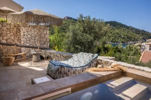 a patio with a couch on a stone wall at Chromata Assos Villas Kefalonia in Asos
