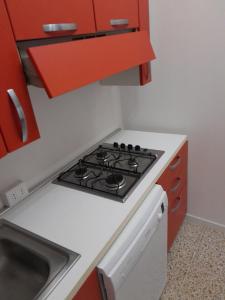 Il comprend une cuisine équipée d'une cuisinière et de placards rouges. dans l'établissement Da Julia, à Oristano