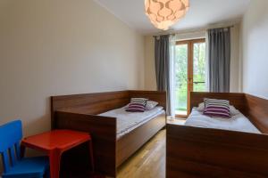 a bedroom with two beds and a chair and a window at Apartament Helios in Jastrzębia Góra