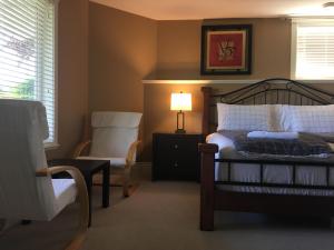 a bedroom with a bed and a chair and a lamp at NeckPoint Treasure BnB in Nanaimo