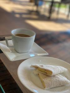 Una taza de café y un plato con un sándwich. en Pousada Brisa do Mar, en Aquiraz