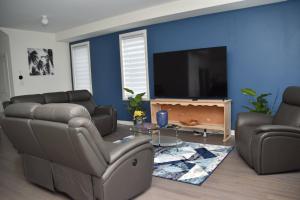 uma sala de estar com um sofá e uma televisão de ecrã plano em PARADISE VILLa em Bowmanville