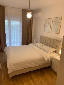 ein Schlafzimmer mit einem weißen Bett und einem Fenster in der Unterkunft Apartman SARA in Trebinje