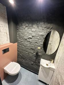 baño con aseo blanco y pared de piedra en DarkHouse FONDOVALLE, en Łódź