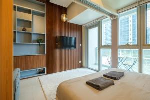 een slaapkamer met een bed, een tv en ramen bij Uptown Parksuites Modern Room in Manilla